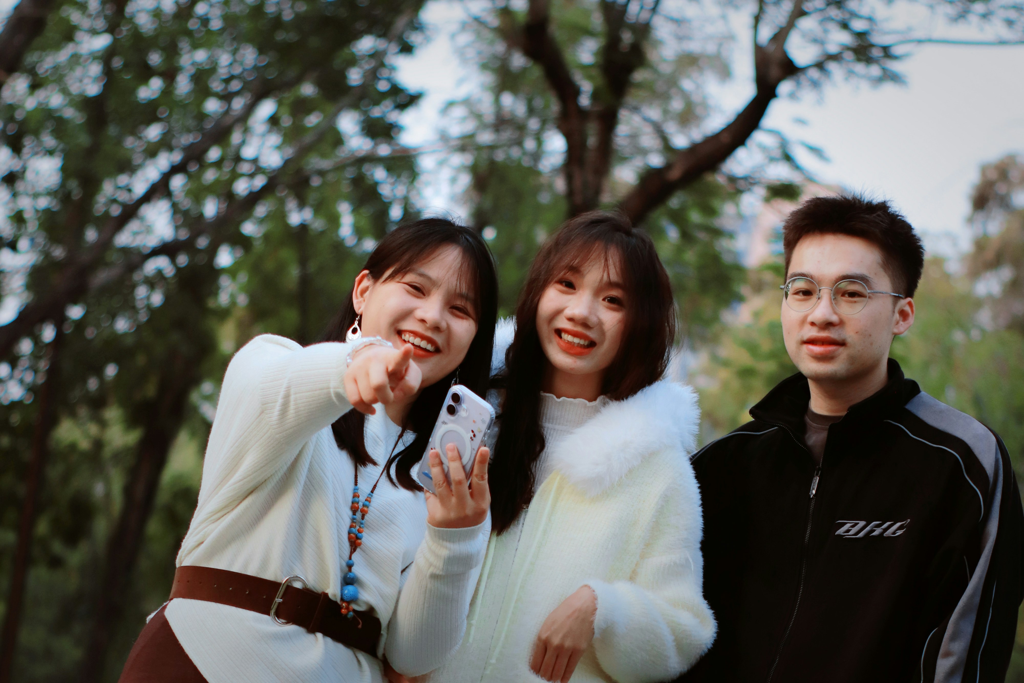 Three smiling friends posing outdoors in a park